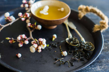 Cup of green tea and peach blossom on dark rustic table as a spring time conceptの写真素材