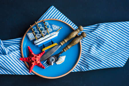Summer vacation marine table setting with rustic plates and silverware on wooden background with copyspaceの写真素材