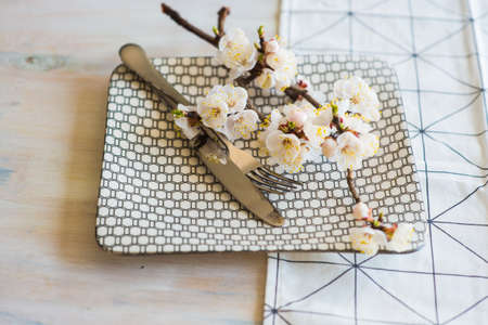 Spring table setting with bright plates and peach blooming on a wooden tableの写真素材