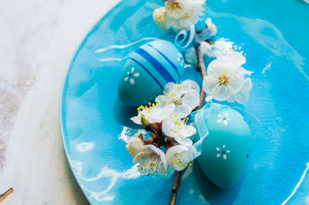 Spring table setting for Easter dinner with bright plates and peach blooming on a wooden tableの写真素材
