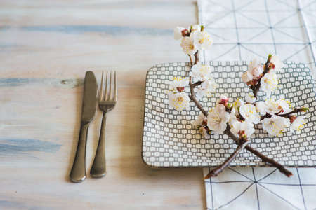 Spring table setting with bright plates and peach blooming on a wooden tableの写真素材