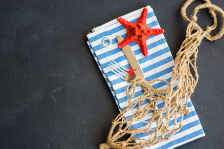 Summer vacation marine table setting with rustic plates and silverware on wooden background with copyspaceの写真素材