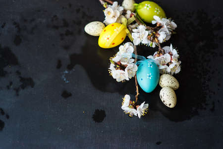 Spring table setting for Easter dinner with bright plates and peach blooming on a wooden table