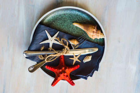 Summer vacation marine table setting with rustic plates and silverware on wooden background with copyspaceの写真素材