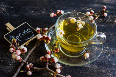 Cup of green tea and peach blossom on dark rustic table as a spring time conceptの写真素材