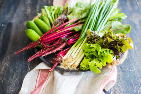 Organic vegetables like a beets, green onion, rukkola, lettuce on dark wooden backgroundの写真素材