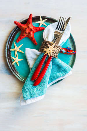 Summer vacation marine table setting with rustic plates and silverware on wooden background with copyspaceの写真素材