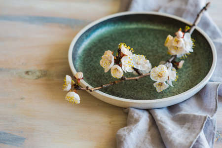 Spring table setting with bright plates and peach blooming on a wooden tableの写真素材