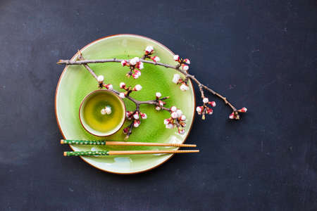 Cup of green tea and peach blossom on dark rustic table as a spring time conceptの写真素材
