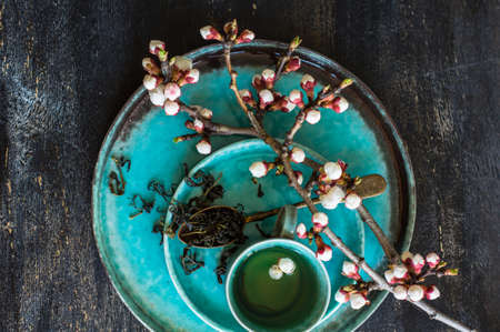 Cup of green tea and peach blossom on dark rustic table as a spring time conceptの写真素材