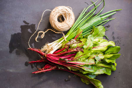 Fresh organic beet with leaves and green onion on dark wooden backgroundの写真素材