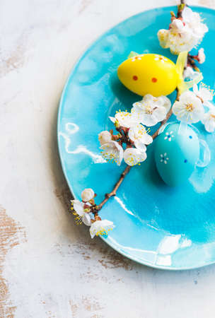 Spring table setting for Easter dinner with bright plates and peach blooming on a wooden tableの写真素材