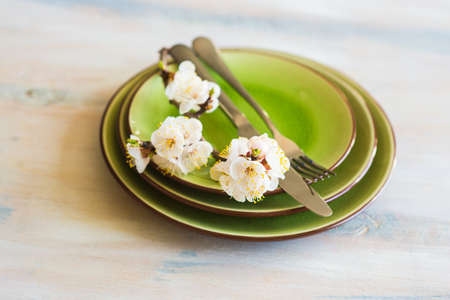 Spring table setting with bright plates and peach blooming on a wooden tableの写真素材