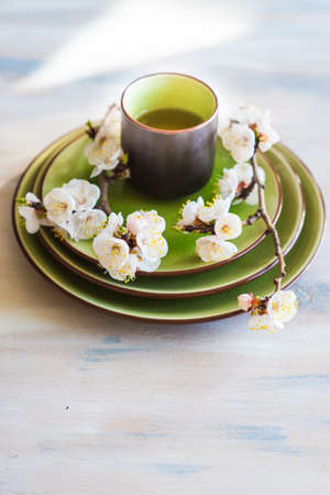 Cup of green tea and peach blossom on dark rustic table as a spring time conceptの写真素材