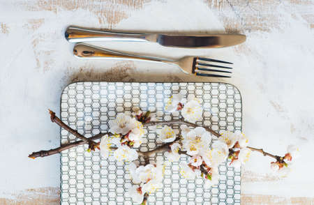 Spring table setting with bright plates and peach blooming on a wooden table