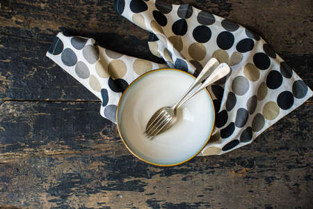 Rustic table setting with vintage bowls and silverware on dark old wooden table with copyspace