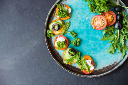 Bruschetta with cheese and vegetables on dark wooden table
