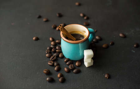 Mug with black coffee, coffee beans, milk and sugar on dark wooden table