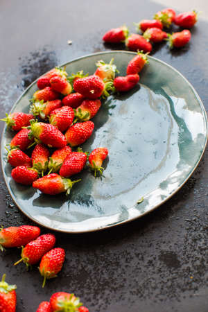 Fresh organic strawberries in rustic ceramic plates on dark wooden background with copyspaceの写真素材