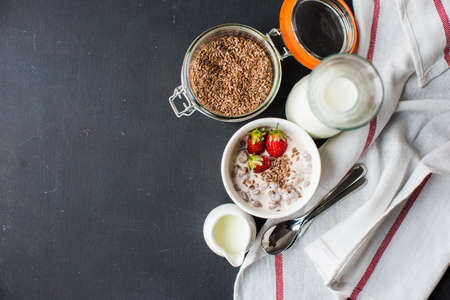 Healthy breakfastwith oats, yogurt, flax seeds and strawberries on dark tableの写真素材