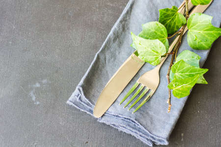 Rustic table setting with vintage ceramic plates and branch of ivy plant on dark old wooden table...