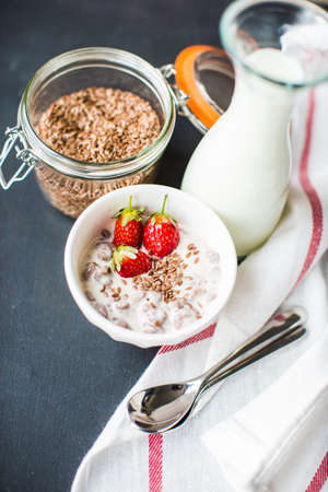 Healthy breakfastwith oats, yogurt, flax seeds and strawberries on dark tableの写真素材