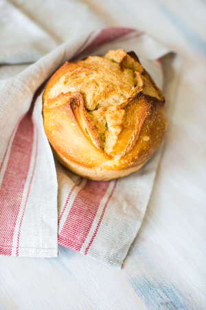 Fresh homemade bread with rustic towel on dark wooden table with copyspace