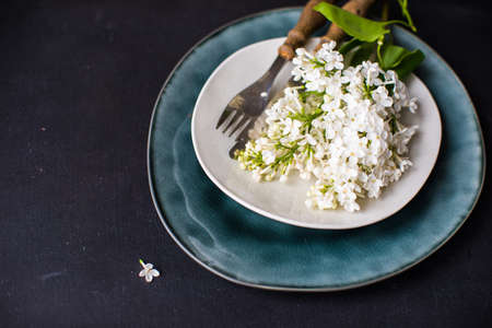 pring table setting with white lilac flowers on the plate with flatware on rustic wooden tableの写真素材