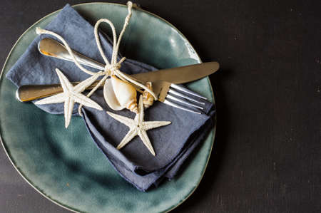 Summer vacation marine table setting with rustic plates and silverware on wooden background with copyspaceの写真素材