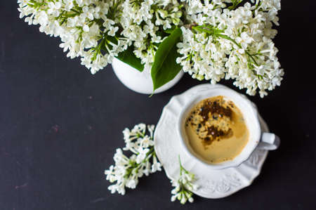 Cup of morning coffee and white lilac flowers on dark wooden tableの写真素材