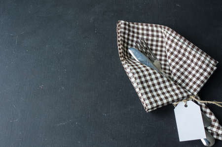 Rustic table setting with napkin and flatware on dark tableの写真素材