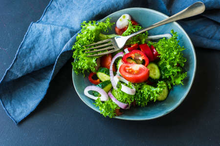 Summer organic salad with fresh vegetables on rustic plateの写真素材