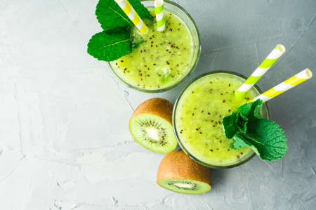 Organic food concept of fresh kiwi smoothie on grey concrete background with fruits and mintの写真素材
