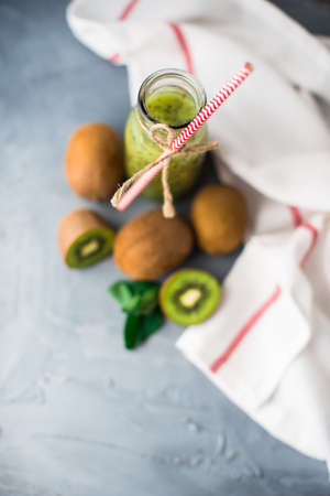 Organic food concept of fresh kiwi smoothie on grey concrete background with fruits and mintの写真素材