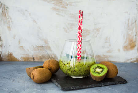Organic food concept of fresh kiwi smoothie on grey concrete background with fruits and mintの写真素材