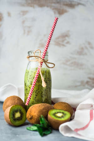 Organic food concept of fresh kiwi smoothie on grey concrete background with fruits and mintの写真素材