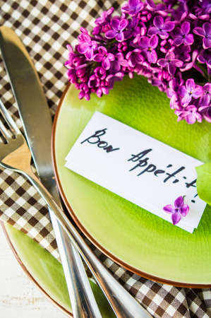 Spring table setting with bright lilac flowers on rustic background with copyspace
