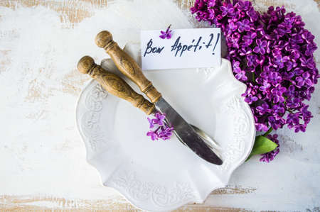 Spring table setting with bright lilac flowers on rustic background with copyspace