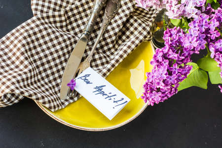 Spring table setting with bright lilac flowers on rustic background with copyspace