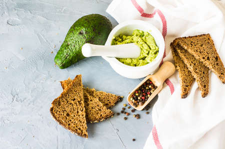 Healthy food concept with bread and avocado vegetable on natural background in rustic style