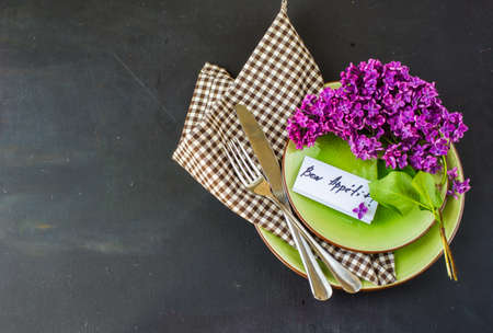 Spring table setting with bright lilac flowers on rustic background with copyspace