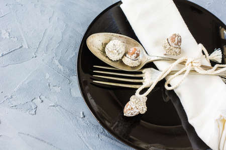 Autumnal table setting with acorns and rustic plates on concrete table