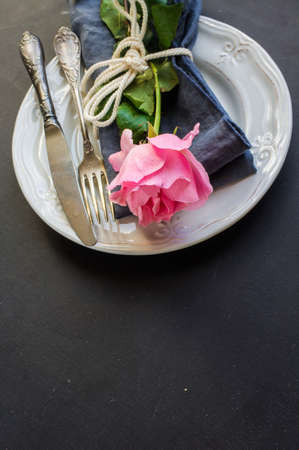 Summer festive table setting with beautiful roses and vintage flatware on dark wooden tableの写真素材