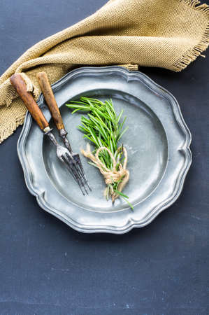 Rustic table setting with rosemary on dark wooden table with copyspaceの写真素材