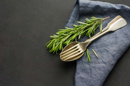 Rustic table setting with rosemary on dark wooden table with copyspaceの写真素材