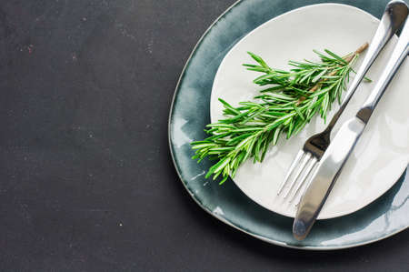 Rustic table setting with rosemary on dark wooden table with copyspaceの写真素材