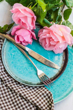 Summer festive table setting with beautiful roses and vintage flatware on dark wooden tableの写真素材