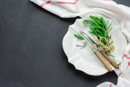 Rustic table setting with rosemary on dark wooden table with copyspaceの写真素材