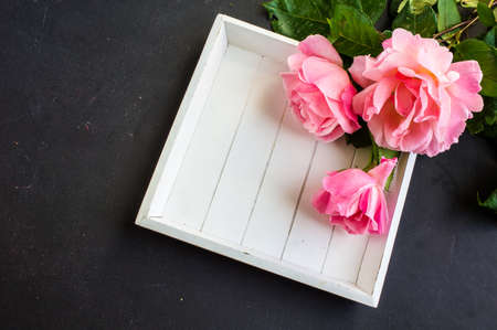 Summer frame with roses on dark wooden background