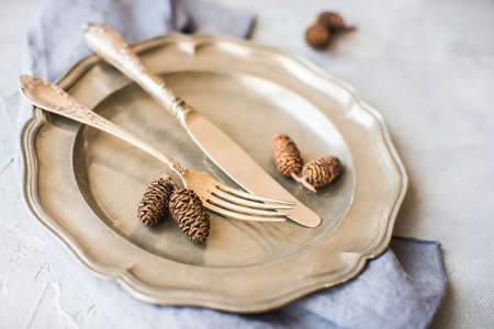 Autumnal table setting with acorns and rustic plates on dark wooden tableの写真素材